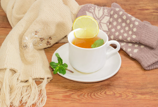 Cup of tea on background of woolen mittens and scarf