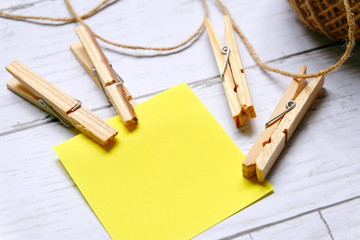 Miscellaneous theme. Top view of empty yellow sticky notes brown rope and cloth pegs on wooden...