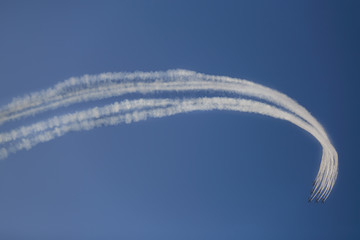 Reactive jet plane flying in formation and leave inversion trail on blue sky