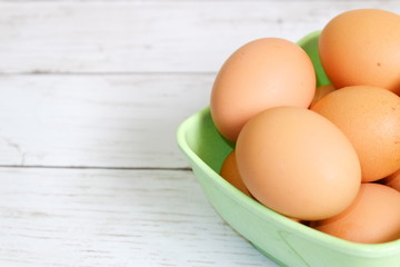 Selective focus of an eggs on a green bowl on a wooden background. Copy space for text or logo.