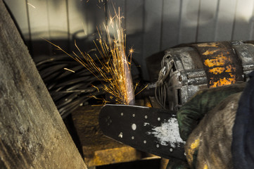 The man in gloves on sandpaper sharpens the knife. Sparks are flying