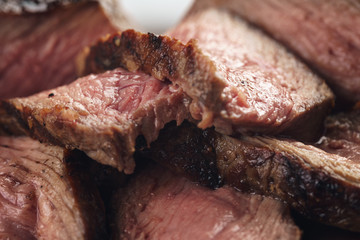 sliced beef steack with pepper on white plate closeup