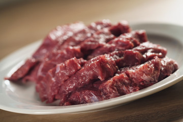 slices of raw beef in white plate on kitchen table