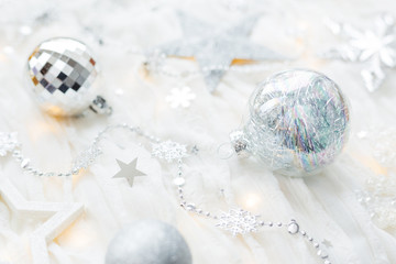 Christmas and New Year holiday background with decorations and light bulbs. Silver and white shining balls, snowflakes and star confetti.