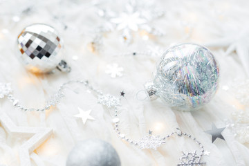 Christmas and New Year holiday background with decorations and light bulbs. Silver and white shining balls, snowflakes and star confetti.