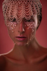 Woman with beads on face and pearl hairhoop