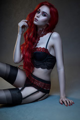 Beautiful gothic woman in lingerie posing at camera on black background