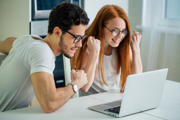 Surprised Shocked couple watching something on laptop at home