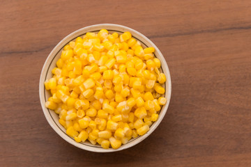 Canned sweet corn in a bowl on wooden table