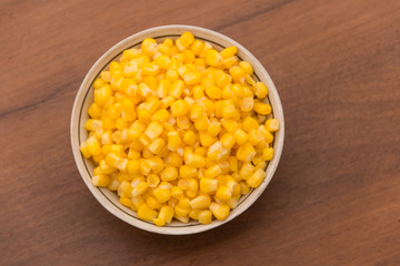 Canned sweet corn in a bowl on wooden table