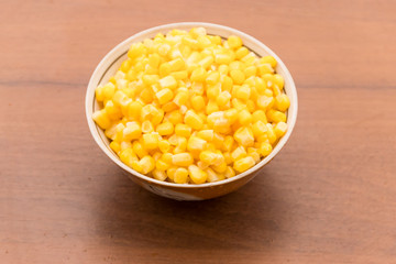 Canned sweet corn in a bowl on wooden table