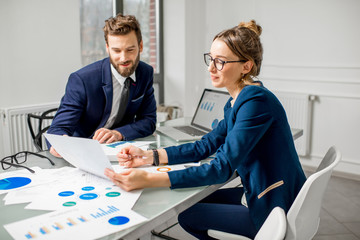 Marketer or analityc manager team dressed in suits working with paper charts and laptops at the...