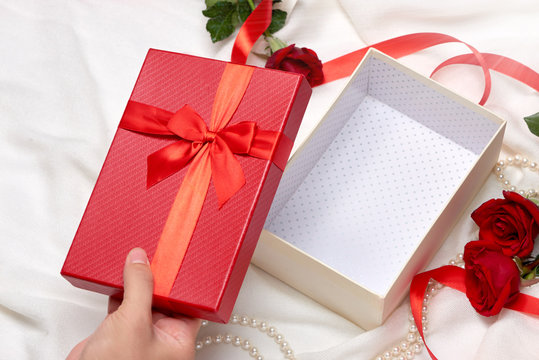 Open empty gift box. Red ribbon bow present with red roses on holiday