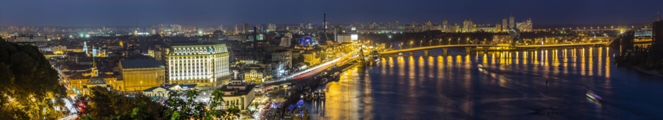 Fototapeta na wymiar Kyiv (Kiev) city, the capital of Ukraine at night beside the Dnipro (Dniepr) river with reflection in water