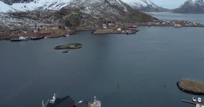 LOFOTEN, NORWAY – FEBRUARY,2017 : Aerial shot over Lofoten cityscape at daytime with harbor and snowy mountains in view