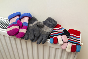 Children's warm hand knitted striped woolen gloves drying on hea