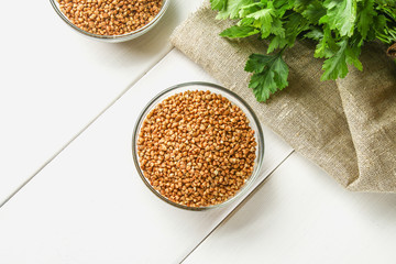 Raw buckwheat in glass bowls on sackcloth on a wooden background. Healthy diet food.