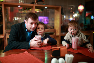 Obraz na płótnie Canvas Father with two sons drinking milkshake