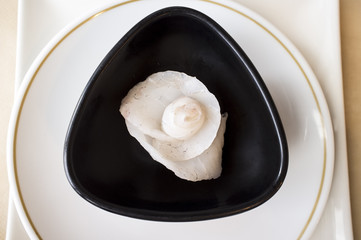 Fototapeta na wymiar Rose flower shaped cod Sashimi Sushi over black bowl. Closeup