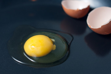 Broken egg with shell on a frying pan.