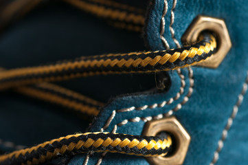 Orange, black shoelace , blue leather boot close up macro shot. - obrazy, fototapety, plakaty