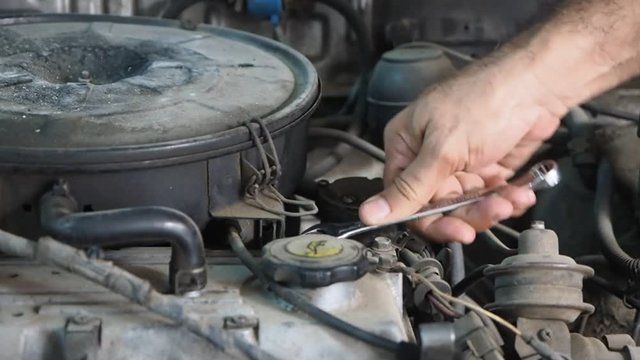 closeup hand of a man repairing engine of a car
