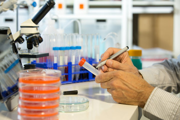 Microbiologist working in laboratory with Petri dishes and pipette