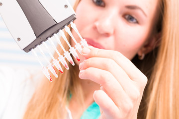 The lab technician examines the results of biochemical tests using a pipette