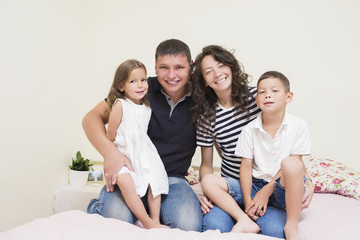 Family Ideas. Happy caucasian Family of Two Parent and Two Kids Sitting Together Embraced and Smiling Happily.