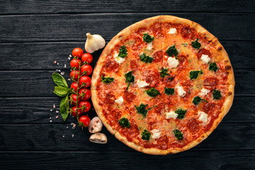 Neapolitan Pizza. Spinach, gorgonzola cheese, sausage salami. On a wooden background. Top view.