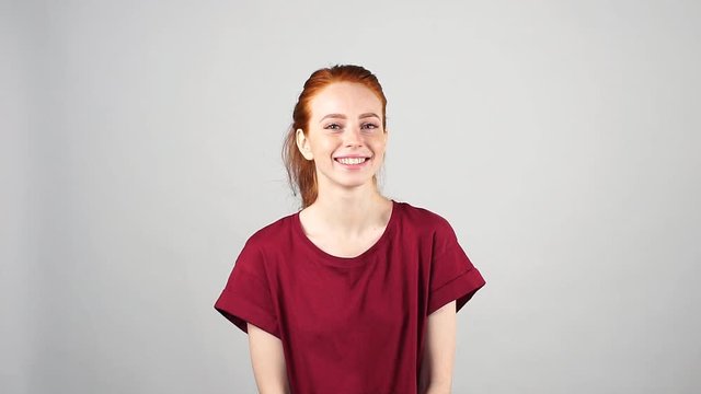 Pretty cheerful redhead girl laughs on the camera on white background in slow motion.