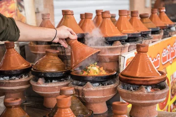 Papier Peint photo Plats de repas Préparation des aliments dans un plat traditionnel tajin au Maroc - viande et légumes dans un tajine en céramique.