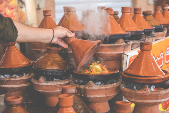 Preparing food in tajin traditional dish in Morocco - meat and vegetable in a ceramic tajine.