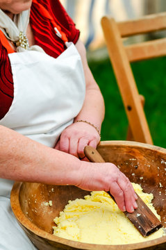 An elderly Irish lady uses a paddle to hand-make butter.