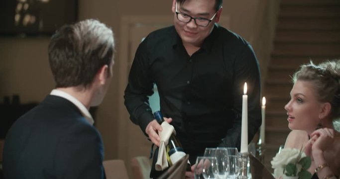 the young Asian waiter serving couple in restaurant for dinner by candlelight