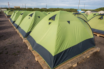 A large number of tents on a sandy beach, lined up strictly in a row.