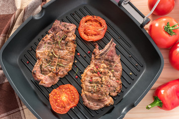 Grilled steak on grill pan with tomatoes on wooden background