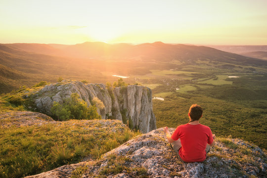 Man sitting on a rocky hill and enjoy the sunset