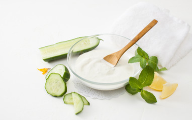 Cut young cucumbers and sour cream on a white background