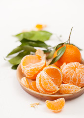 Peeled tangerines and peel with leaves on white background