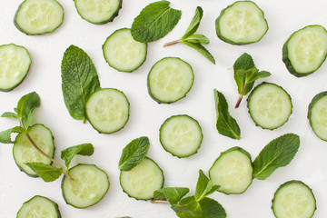 Background of sliced cucumbers with sprigs of greenery