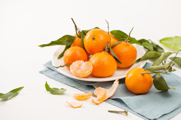 Peeled tangerines and peel with leaves on white background