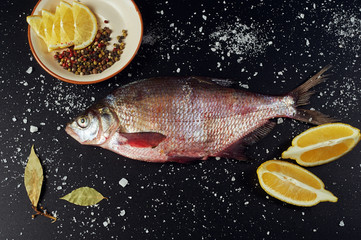 Fototapeta na wymiar Fresh fish. River fish and ingredients for cooking on a dark background. The view from the top