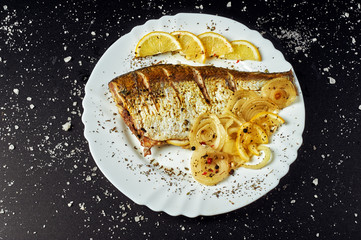 Baked fish in foil on a dark background . The view from the top