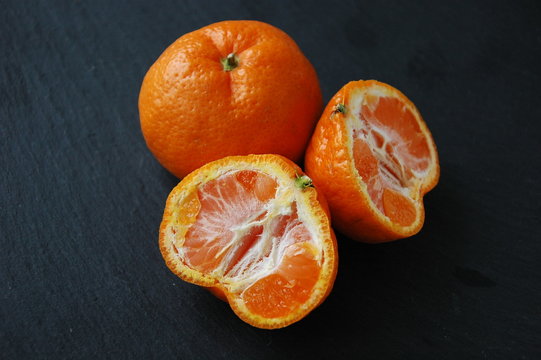 A few tangerines close-up on a black background.
