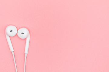 Top view Lovely Closeup of White Earphones on Pink Pastel plastic texture background. Pastel color concept, Minimal concept. Copy space. Music is my life concept. Valentine concept