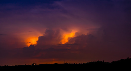 Blitze und Wetterleuchten über Hügliger Landschaft