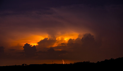 Blitze und Wetterleuchten über Hügliger Landschaft