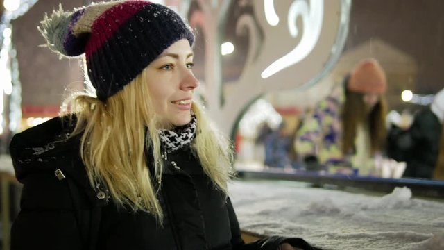 Young beautiful happy girl walks near ice rink and looks around for other people