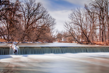 Long exposure exterior daytime stock photo of waterfall and felled log with blue sky background in Batavia New York in Genesee County